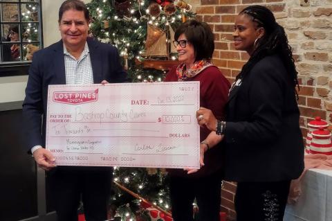 Carlos Liriano (left), Lost Pines Toyota owner, hands a check of $10,000 to representatives of Bastrop County Cares during a December 2022 presentation.   Courtesy photo