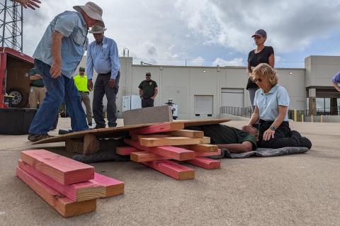 Participants in the FEMA G317 Introduction to Basic CERT Course access the emergency simulating a person trapped under rubble. They practiced the cribbing technique, using temporary wooden structure to support heavy objects. Photo courtesy of Bastrop County Office of Emergency Management