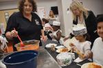 Candy Biehle (left), Smithville ISD child nutrition director, serves results of a food demonstration to elementary students in Smithville March 22. Superintendent Cheryl Burns assists at right. Photo by Fernando Castro